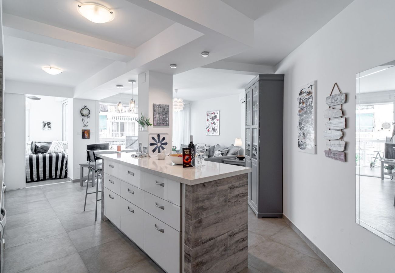 Matplats med träbord och designstolar intill det utrustade köket i Nerja.