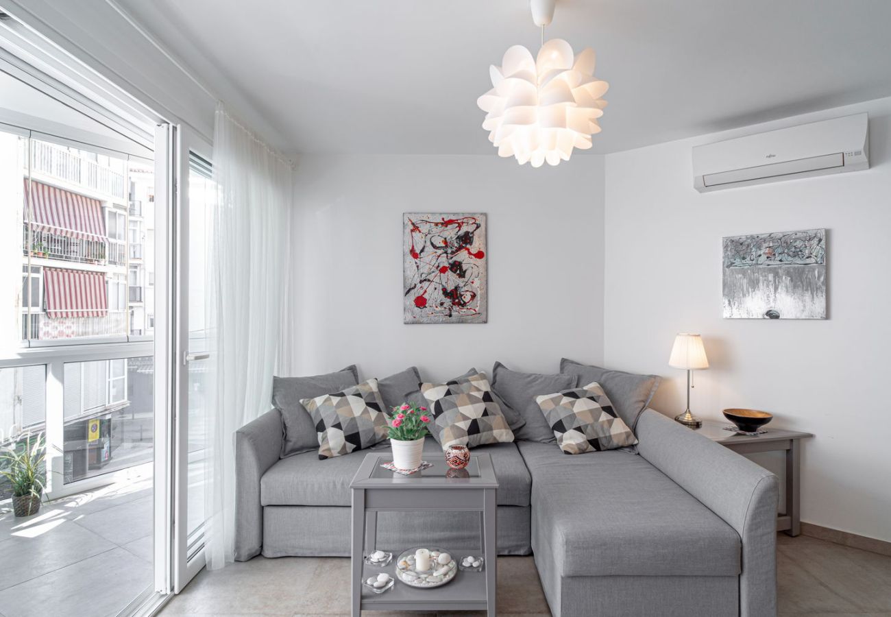 Ljust vardagsrum med designsoffa och direkt tillgång till inglasad balkong i Nerja centrum.
