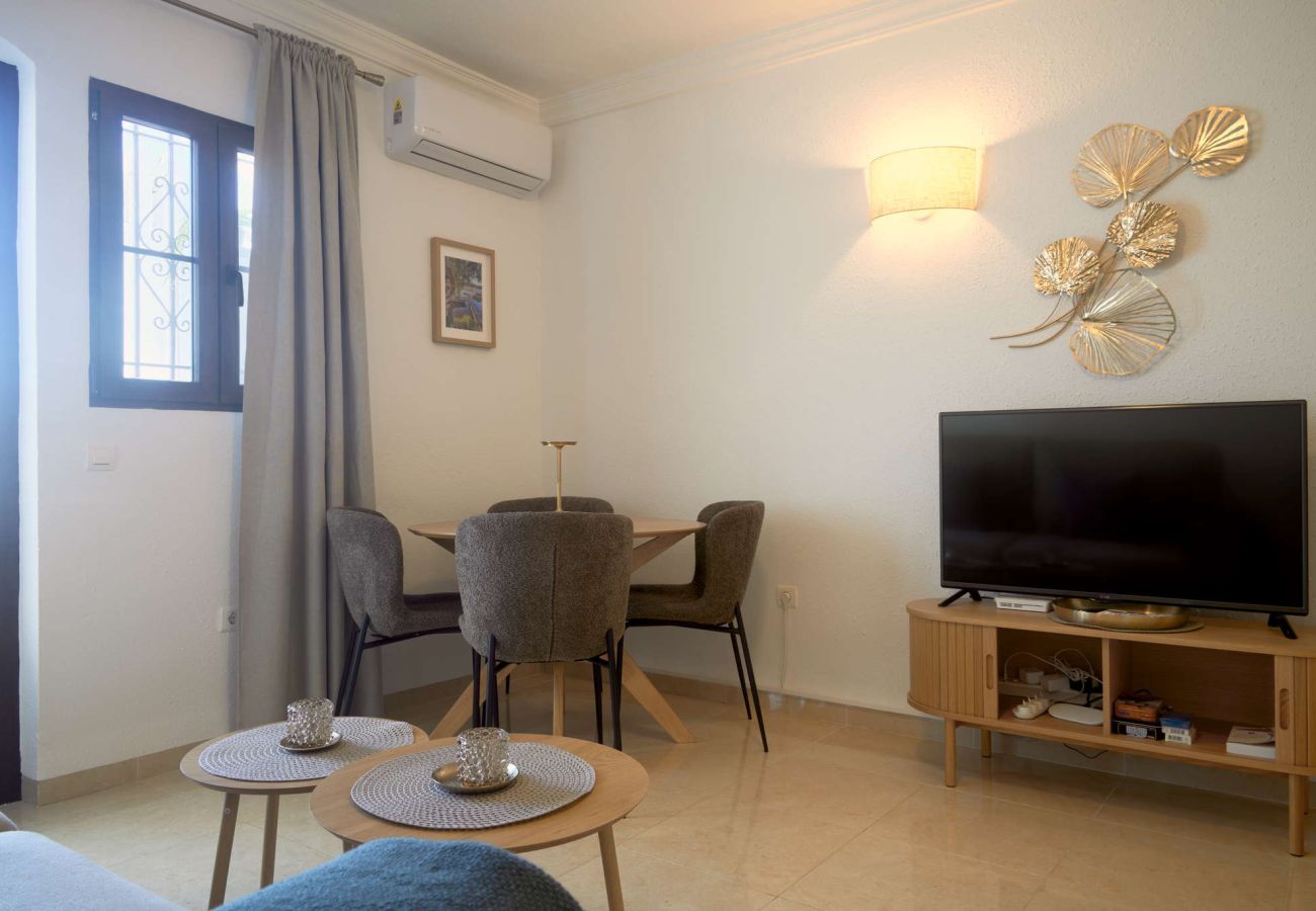 Ljus interiör i vardagsrum och matplats med tillgång till terrassen i Capistrano Village Nerja.