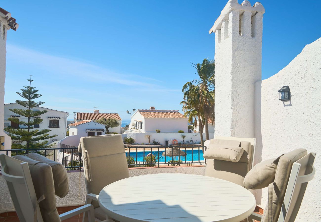 Privat terrass i Capistrano Village Nerja med matbord och utsikt över den gemensamma poolen.