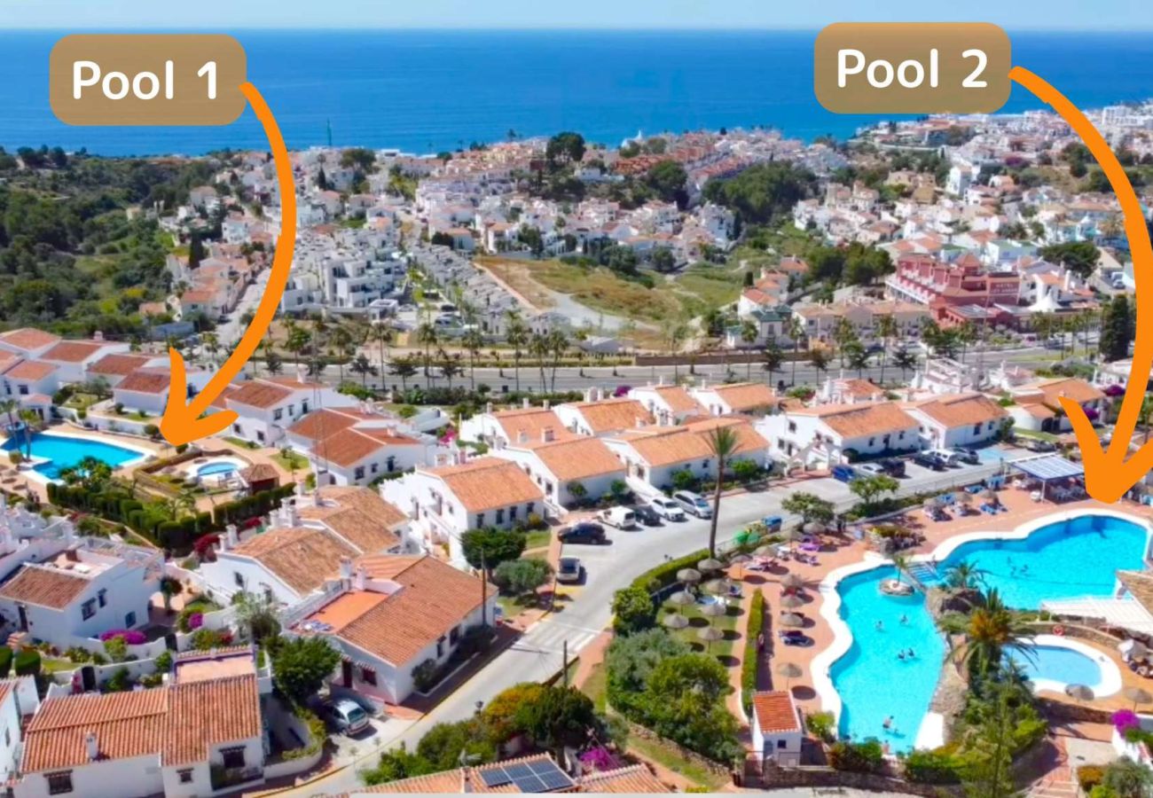 Flygvy över Capistrano Village Nerja som visar de vita husen och de två gemensamma poolerna.